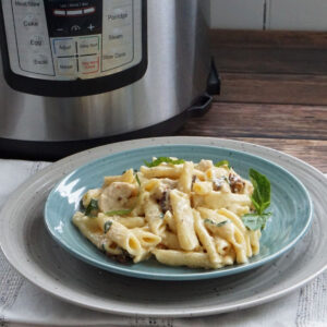 A plate of chicken pasta in front of the Instant Pot