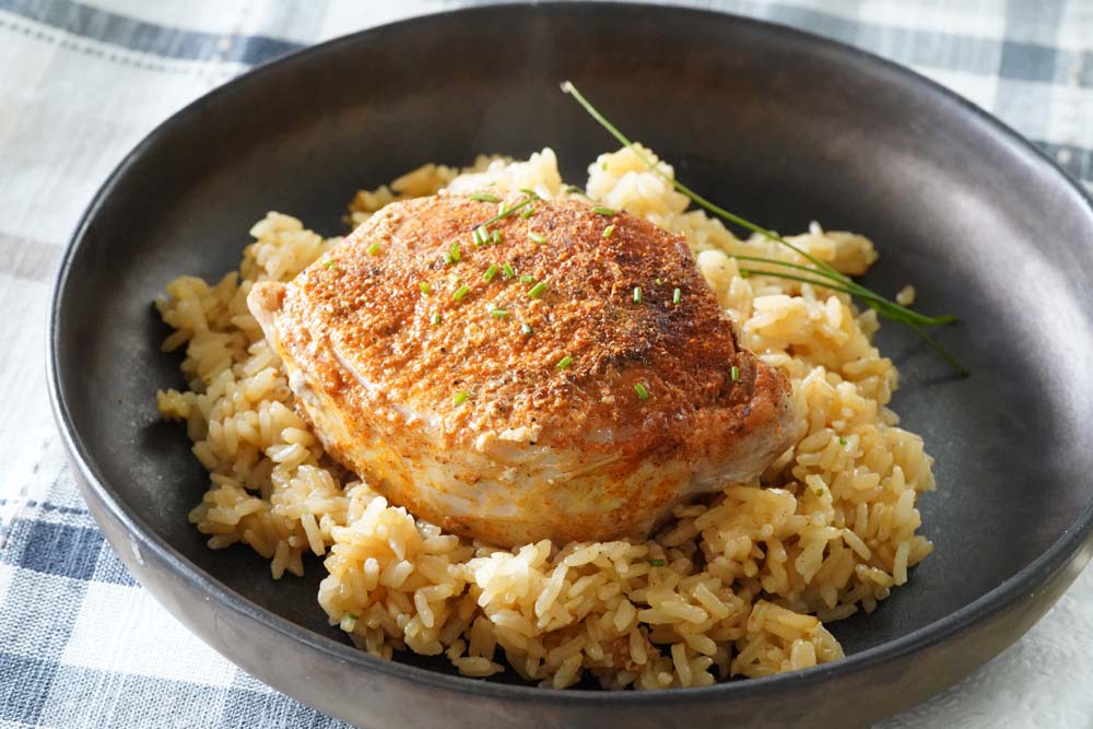 A pork chop on a bed of rice