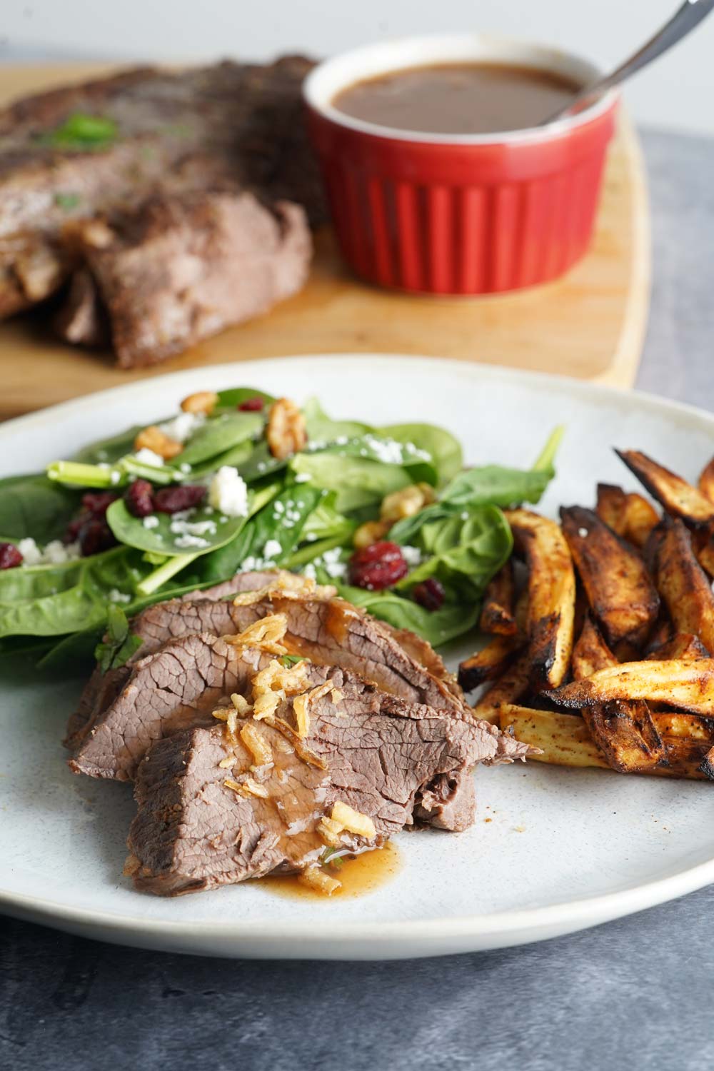 Sliced London broil on a plate with salad and parsnips