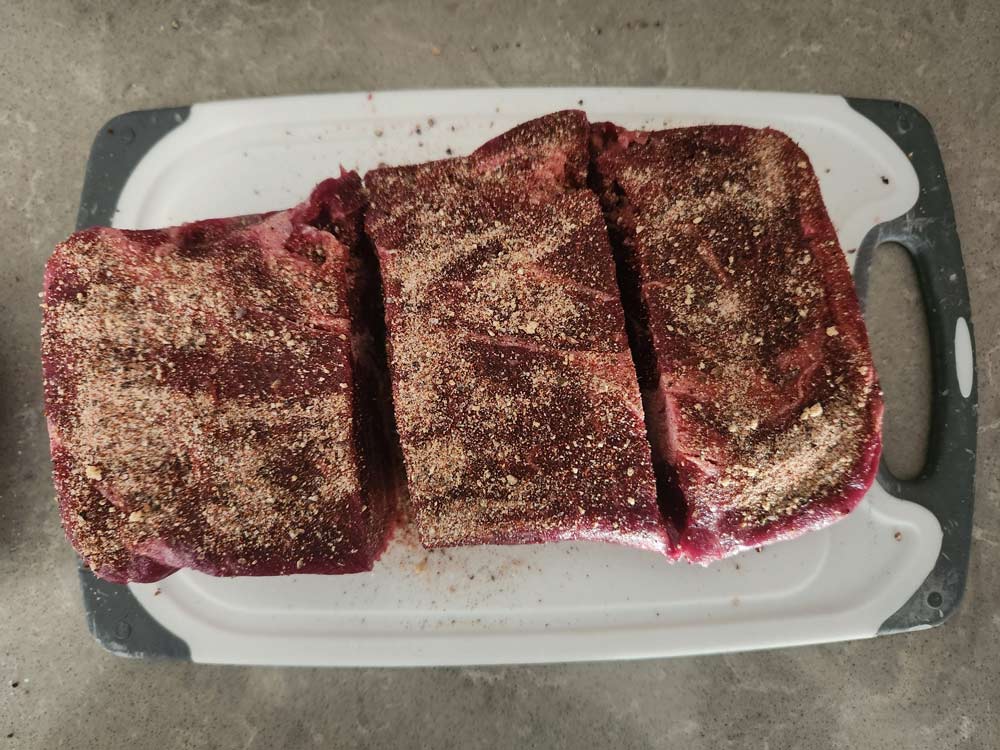 Seasoned beef cut into pieces on a cutting board