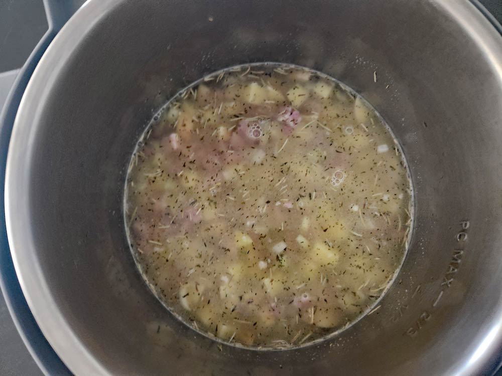 Adding broth to the soup to pressure cook.